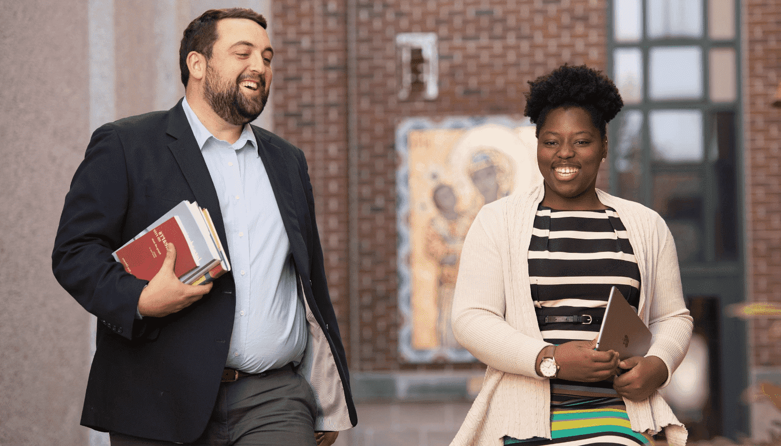 Two online Loyola students having a discussion as they walk across campus.